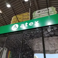 Atex Pilchowice: ceny węgla. Różne rodzaje węgla w gablotach, nad nimi logo Atex i paczki z ekogroszkiem.