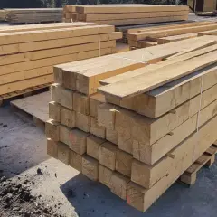Stosy drewnianych belek, gotowe do transportu. Skład drewna machnik oferuje materiały budowlane najwyższej jakości.