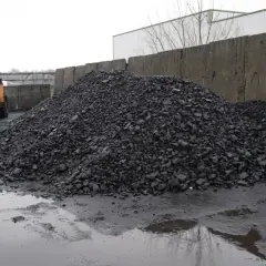 Ogromna hałda węgla przy placu budowy, gdzie koparka przygotowuje materiał. Może to być związane z dopłatami do węgla.