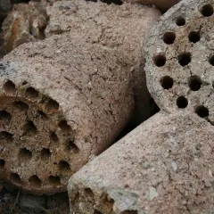 Brykiety z węgla brunatnego, gotowe do użycia. Pokazują, jak działa brykieciarka, sprasowując materiał w cylindryczne kształty z otworami.