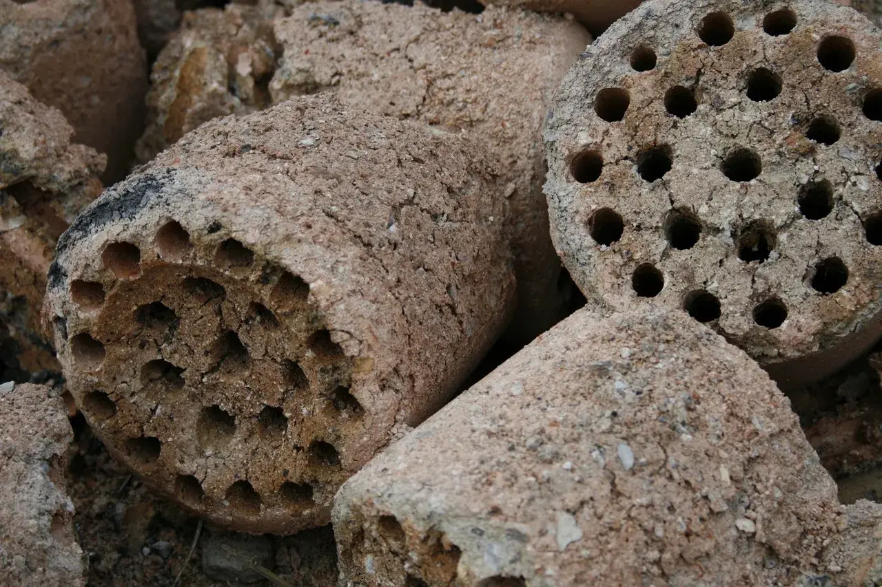 Brykiety z węgla brunatnego, gotowe do użycia. Pokazują, jak działa brykieciarka, sprasowując materiał w cylindryczne kształty z otworami.