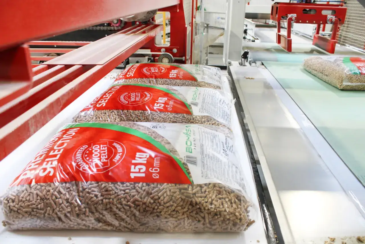 Work in progress: workujące opakowania z pelletem drzewnym na linii produkcyjnej, pokazujące, jak powstaje pellet.