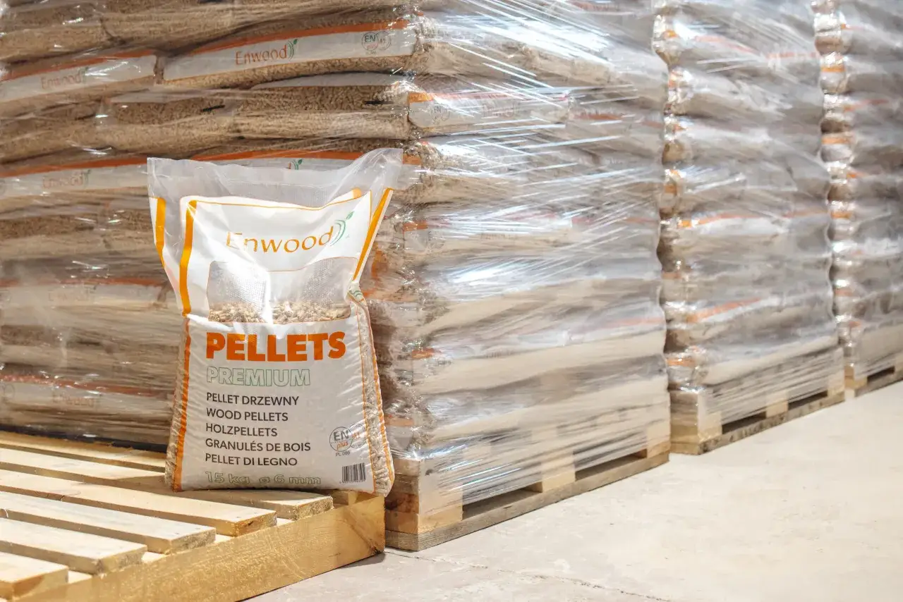Paleta z workiem pelletu premium Enwood z certyfikatem ENplus A1. W tle stosy worków pelletu owinięte folią.